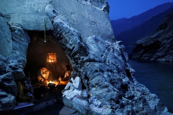 Индусские священники сидят в пещере во время вечерней молитвы на берегу реки Ганг в Девпраяге, Индия. - Sputnik Молдова