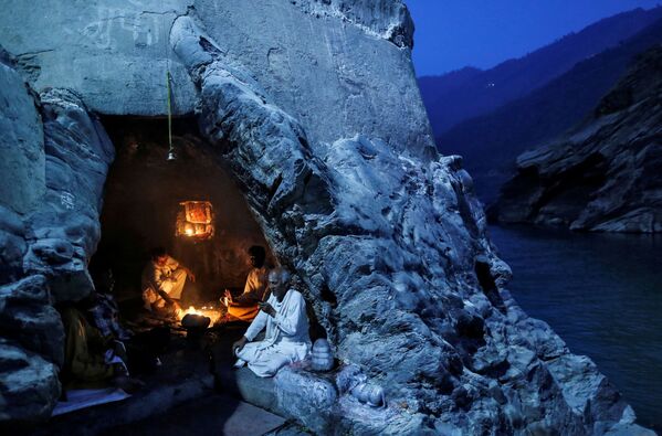 Preoții hinduși stau într-o peșteră în timpul rugăciunii de seară pe malurl râului Gange din Devprayag, India. - Sputnik Moldova