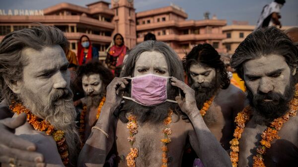 Нага Садху надевает маску перед процессией для купания в реке Ганг на Фестивале кувшинов в Харидваре, Индия - Sputnik Молдова