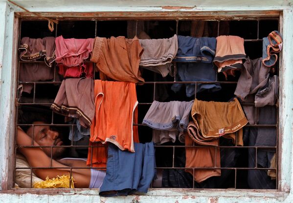 Un locuitor al mahalalelor doarme lângă o fereastră acoperită cu haine pentru a se usca într-o baracă din Dharavi, Mumbai.  - Sputnik Moldova-România
