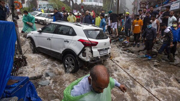 Люди пытаются вытянуть автомобиль, поврежденный во время наводнений после сильных муссонных дождей в Индии - Sputnik Молдова