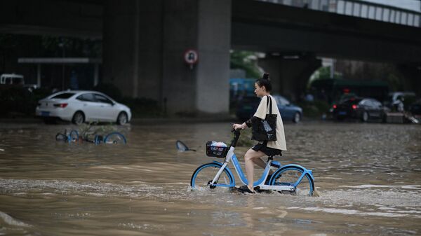 Девушка едет на велосипеде на затопленной улице в китайской провинции Хэнань  - Sputnik Молдова