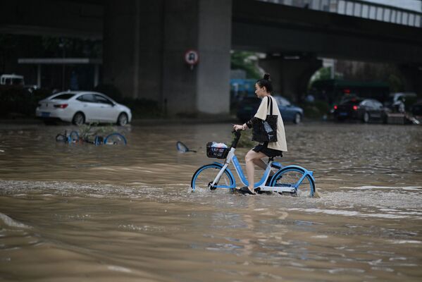 Девушка едет на велосипеде на затопленной улице в китайской провинции Хэнань - Sputnik Moldova