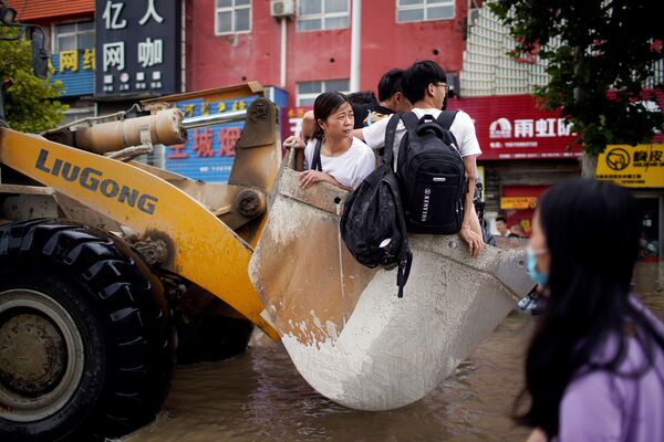 Люди, едущие на фронтальном погрузчике, после проливного дождя в Чжэнчжоу, Китай. - Sputnik Молдова