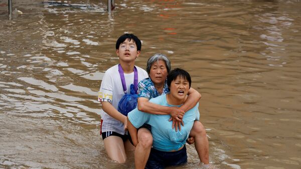 Женщина несет пожилую женщину  через паводковые воды после проливного дождя в Чжэнчжоу, провинция Хэнань, Китай - Sputnik Moldova-România