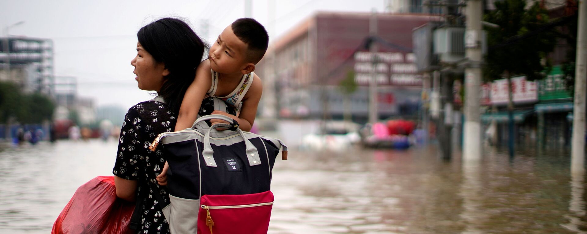 Женщина с ребенком и вещами пробирается через паводковые воды после проливного дождя в Чжэнчжоу, провинция Хэнань, Китай - Sputnik Молдова, 1920, 26.07.2021