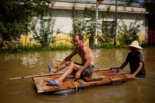 Sătenii strabat apele în urma inundațiilor după precipitațiile abundente într-un sat din Xinxiang, provincia Henan, China, 24 iulie 2021. - Sputnik Moldova-România