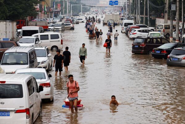 Oamenii străbat apele după precipitațiile abundente în Zhengzhou, provincia Henan, China, 23 iulie 2021. - Sputnik Moldova-România