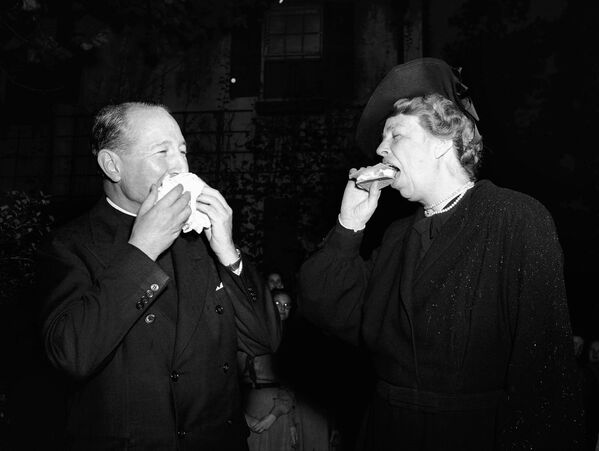 Элеонора Рузвельт и преподобный Эдвард Робертс Мур пробуют гамбургеры, приготовленные герлскаутами на открытом огне, во время празднования Национальной недели герлскаутов. - Sputnik Молдова