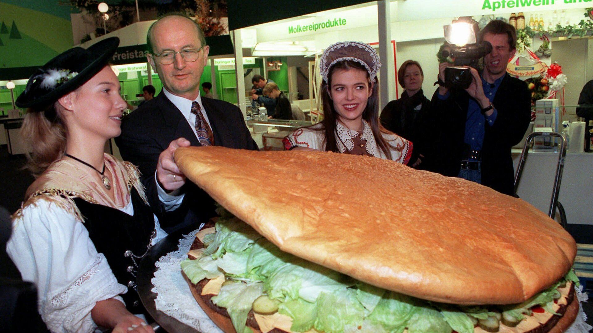  Министр сельского хозяйства Германии Йохен Борхерт проверяет гигантский гамбургер во время посещения Gruene Woche, крупнейшей в мире ярмарки продуктов питания и сельского хозяйства, в Берлине - Sputnik Moldova, 1920, 12.03.2022