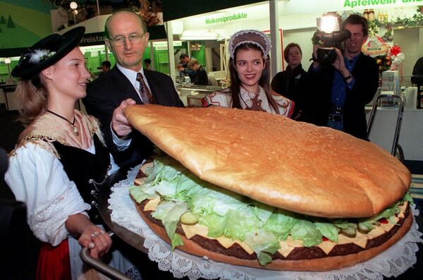 Министру сельского хозяйства Германии Йохену Борхерту презентуют гигантский гамбургер на крупнейшей в мире ярмаркой продовольствия и сельского хозяйства &quot;Зеленая неделя&quot; (Gruene Woche), проходившей в Берлине в 1997 году. Гамбургер был изготовлен только из немецких продуктов. - Sputnik Молдова