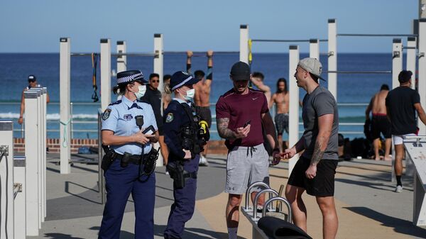 Ofițerii de poliție verifică actele de identitate în timp ce pun în aplicare un blocaj al coronavirusului într-o zonă de gimnastică în aer liber de pe plaja Bondi, în Sydney, Australia, 27 iulie 2021 - Sputnik Moldova-România