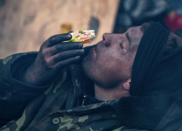 Участник акции оппозиции ест бутерброд на баррикаде на улице Грушевского в Киеве - Sputnik Молдова