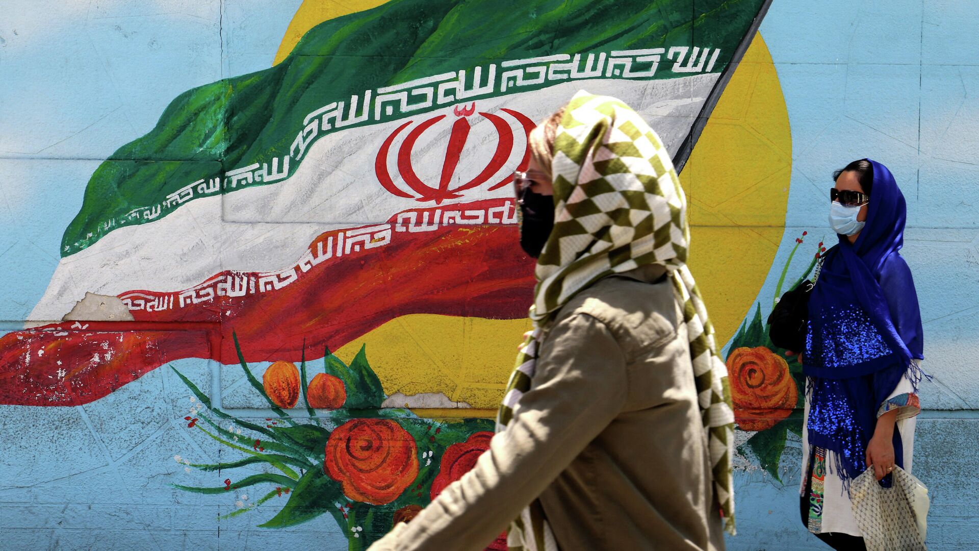 Иранцы в масках проходят мимо фрески с изображением национального флага Ирана в Тегеране  - Sputnik Молдова, 1920, 12.08.2021
