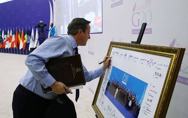 Премьер-министр Великобритании Дэвид Кэмерон подписывает групповое фото лидеров G-20, сделанное накануне на саммите G-20 в Анталии 16 ноября 2015 года. - Sputnik Молдова