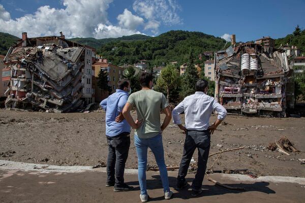 Местные жители смотрят на частично разрушенные здания после наводнений в Бозкурте. - Sputnik Молдова