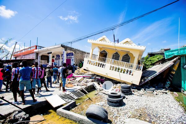 Oamenii stau lângă o casă distrusă în urma unui cutremur cu magnitudinea 7,2 din Les Cayes, Haiti, 14 august 2021. - Sputnik Moldova