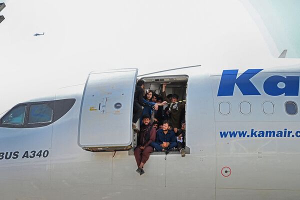 Afganii stau la ușa unui avion așteptând ca avionul de decoleze de pe pista aeroportului din Kabul - Sputnik Moldova