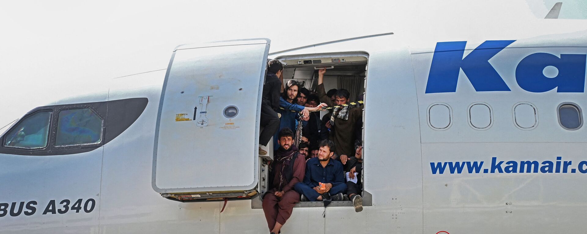 Афганцы сидят в дверях самолета в аэропорту Кабула  - Sputnik Moldova-România, 1920, 17.08.2021
