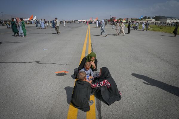 Афганцы сидят вдоль взлетно-посадочной полосы, ожидая выхода из кабульского аэропорта. - Sputnik Молдова