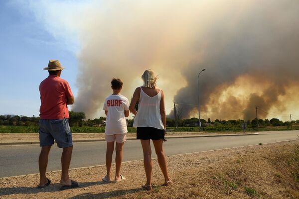Туристы наблюдают с обочины дороги густой дым от возобновившихся лесных пожаров к северу от Гримо, на юге Франции. - Sputnik Молдова