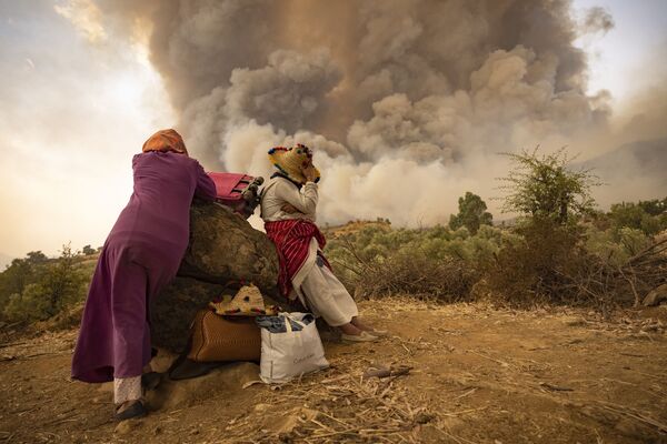 Женщины на горной дороге со своими вещами во время лесных пожаров на севере Марокко. - Sputnik Молдова
