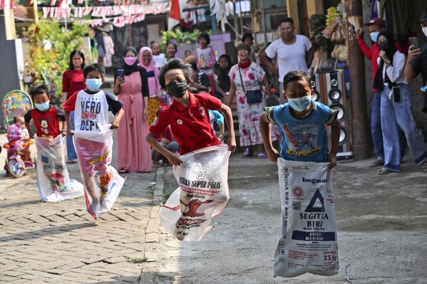 Дети в масках принимают участие в соревнованиях по бегу на мешках во время празднования Дня независимости в Джакарте, Индонезия. - Sputnik Молдова