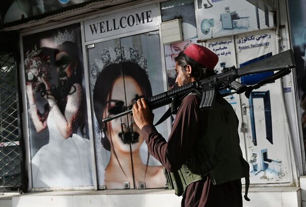 Боевик Талибана* у салона красоты с изображениями женщин, испачканных аэрозольной краской, в Шахр-э Нау в Кабуле. - Sputnik Молдова