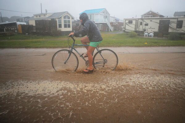 Велосипедист на затопленной улице после тропического шторма &quot;Генри&quot; в США. - Sputnik Молдова