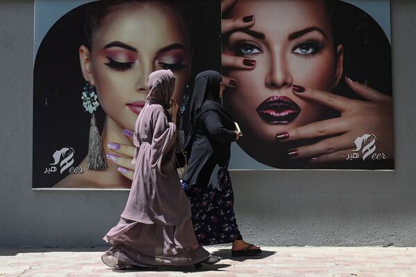 Femeile îmbrăcate în Burqa trec pe lângă un panou publicitar pus pe peretele unui salon de înfrumusețare din Kabul pe 7 August 2021. - Sputnik Moldova-România