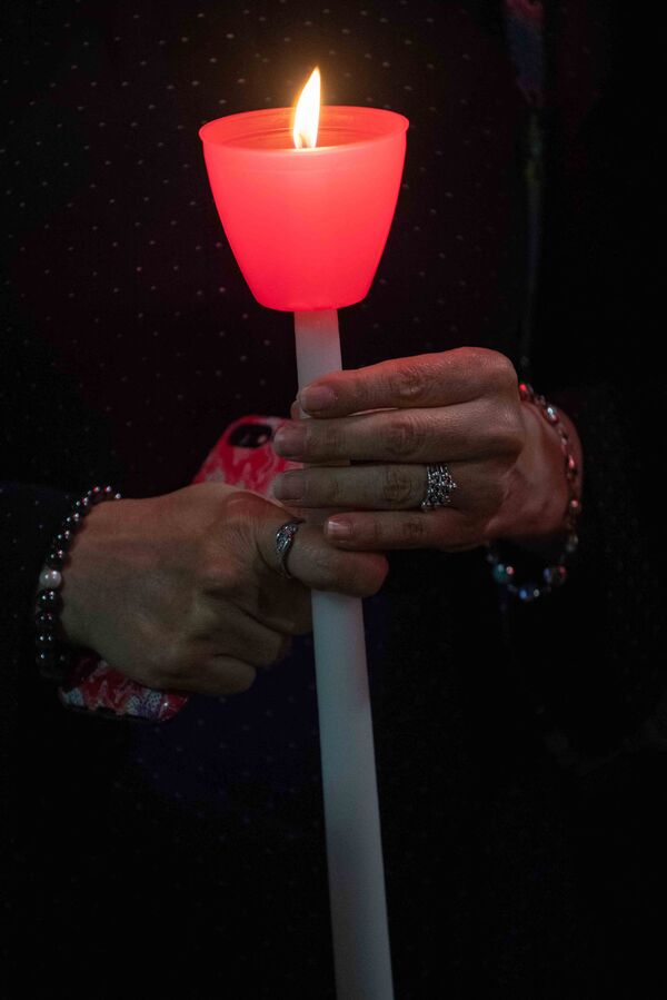 O femeie ține o lumânare aprinsă în timpul unei ceremonii religioase de comemorare 9/11 la Altarul Național Sfântul Nicolae Ortodox Grecesc, adiacent Memorialului și Muzeului 9/11 din New York, pe 10 septembrie 2021. - Sputnik Moldova-România