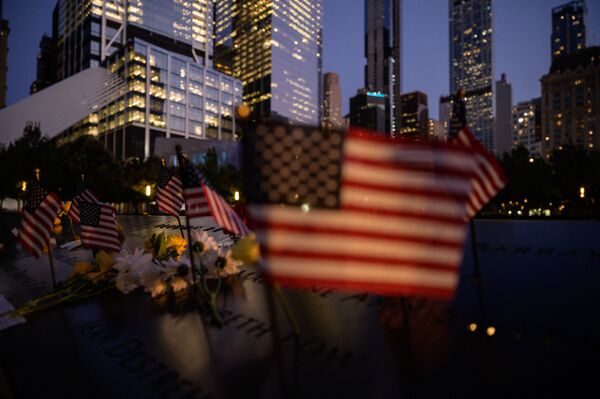 Drapelele SUA sunt arborate în fața unui bazin reflectorizant la Memorialul 9/11 al  victimelor atentatelor teroriste din 2001, New York, 10 septembrie 2021. - Sputnik Moldova