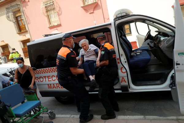 O femeie este ajutată de membrii echipei de salvare, care a sosit la un centrul sportive, după ce a fost evacuate din cauza incendiilor forestiere din muntele Sierra Bermeja. Spania, 12 septembrie 2021. - Sputnik Moldova-România
