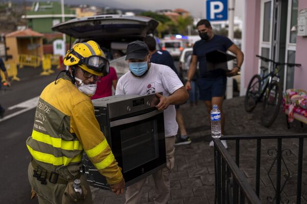 Locuitorii insulei La Palma, Spania, sunt ajutați de salvatori să-și salveze lucrurile din calea lavei a vulcanului erupt. - Sputnik Moldova