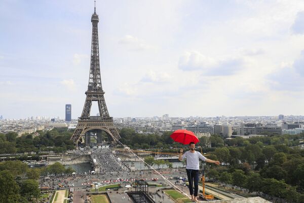 Marinarul francez Nathan Paulin ține o umbrelă în timp ce cântă, pentru a doua oară, pe o funie la înalțime de 70 de metri, care se întinde pe 670 de metri între Turnul Eiffel și Teatrul Național de Chaillot, ca parte a 38-a Zile a Patrimoniului European și lansarea olimpiadei culturale din Paris, pe 19 septembrie 2021.De la primul etaj al Turnului Eiffel până la Teatrul Național de Chaillot, este cea mai lungă traversare de funie la înalțime într-un mediu urban - Sputnik Moldova-România
