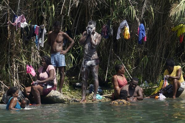 Migranții haitieni fac baie și spălătorie de-a lungul malurilor Rio Grand după ce au trecut în Statele Unite din Mexic, sâmbătă, 18 septembrie 2021, în Del Rio, Texas. SUA intenționează să-și accelereze eforturile de expulzare a migranților haitieni pe zborurile către patria lor din Caraibe, au declarat oficiali sâmbătă, în timp ce agenții se revărsau într-un oraș de frontieră din Texas, unde mii de haitieni s-au adunat după ce au traversat brusc în SUA din Mexic. - Sputnik Moldova-România