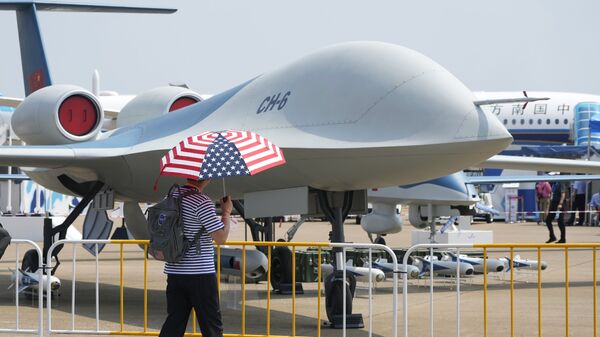 Мужчина с зонтом в цветах флага США у беспилотника CH-6 на Airshow China в Чжухае, Китай - Sputnik Moldova-România