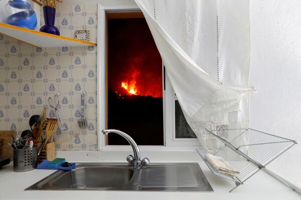 Lava se observă prin fereastra unei bucătării din insula, El Paso în urma erupției unui vulcan de pe Insula Canare din La Palma, Spania, 28 septembrie 2021. - Sputnik Moldova-România