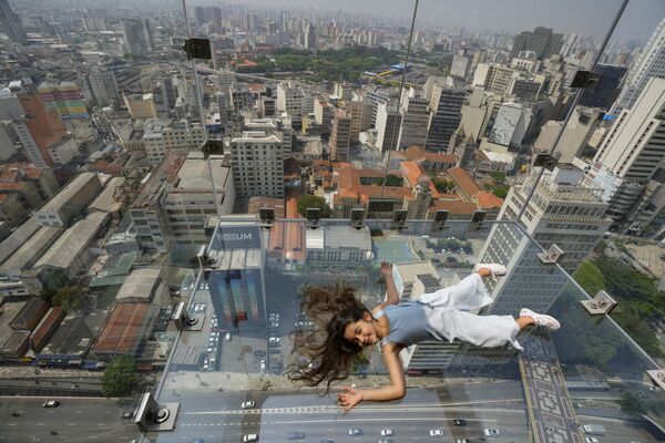 O fată zace pe observatorul Sampa Sky, realizat în întregime din sticlă, la etajul 42 al clădirii Mirante do Vale din centrul orașului Sao Paulo, Brazilia, miercuri, sept. 29, 2021. Punctul de vedere Sampa Sky este o structură de sticlă înaltă de 150 de metri în cea mai înaltă clădire din Sao Paulo. - Sputnik Moldova-România