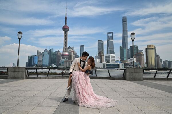 Un cuplu pozează în timpul unei sesiuni foto înainte de nuntă pe promenada de pe Bund de-a lungul râului Huangpu din Shanghai pe 24 septembrie 2021. - Sputnik Moldova-România