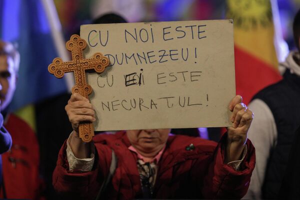Poster și o cruce ținute în mâini de un protestatar la manifestațiile de la București împotriva pașapoartelor COVID și a vaccinării obligatorii - Sputnik Moldova-România