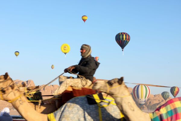 Un bărbat călare pe cămilă în timpul festivalului baloanelor cu aer cald în deșertul Wadi Rum, Iordania. - Sputnik Moldova