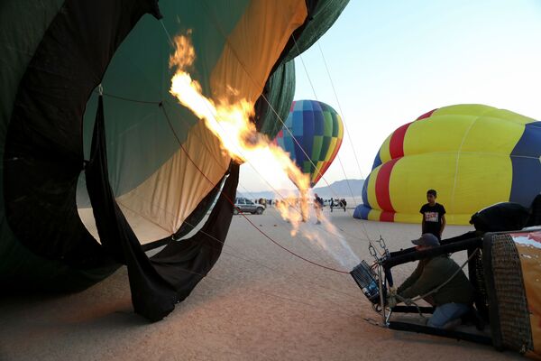 Un muncitor trage arzătorul în interiorul unui balon în timpul festivalului baloanelor cu aer cald în deșertul Wadi Rum, Iordania - Sputnik Moldova