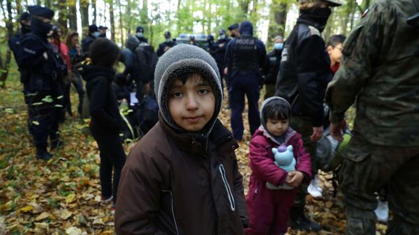 Иракский ребенок в окружении пограничников и полицейских после пересечения белорусско-польской границы в городе Хайнувка, Польша - Sputnik Moldova-România