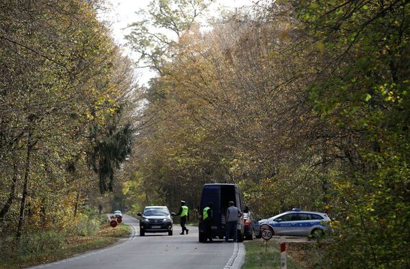 Ofițerii de poliție polonezi examinează vehiculele la un punct de control la intrarea în zona interzisă a statului de urgență, creat pentru a gestiona mai bine o criză a migranților în curs de desfășurare la frontiera belarusă-poloneză lângă Bialowieza, Polonia, 14 octombrie 2021. - Sputnik Moldova-România