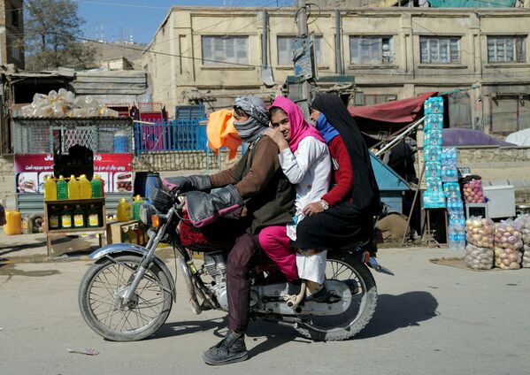 O familie afgană merge cu motocicleta pe lângă magazinele de pe marginea drumului din Kabul, Afganistan, la 16 octombrie 2021. - Sputnik Moldova-România