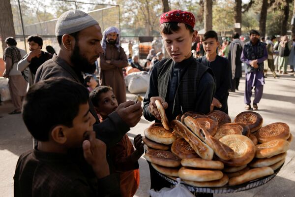Un băiat vinde pâine la un adăpost improvizat pentru familiile afgane strămutate, care fug de violența din provinciile lor, în parcul Shahr-e Naw, din Kabul, Afganistan, 4 octombrie 2021. - Sputnik Moldova-România