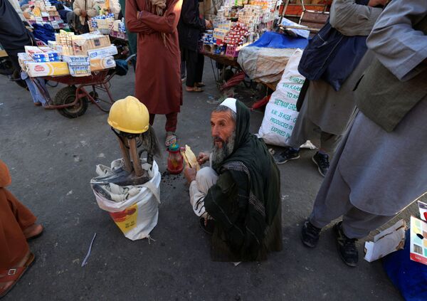 Gul Mohammad, în vârstă de 55 de ani, își ia micul dejun în timp ce stă lângă instrumentele sale în timp ce așteaptă să-și găsească un loc de muncă pe piața Pole Bagh Omomy din Kabul, Afganistan, 15 octombrie 2021. - Sputnik Moldova-România