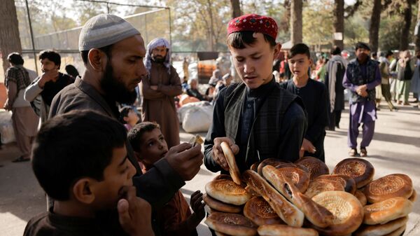 Мальчик продает хлеб во временном убежище для перемещенных афганских семей, спасающихся от насилия в своих провинциях, Кабул - Sputnik Moldova