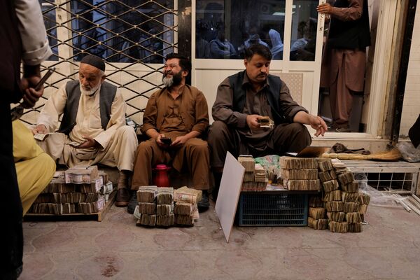 Bărbați afgani stau în spatele teancurilor de bancnote la o piață de schimb valutar din Kabul, Afganistan, 7 octombrie 2021. - Sputnik Moldova